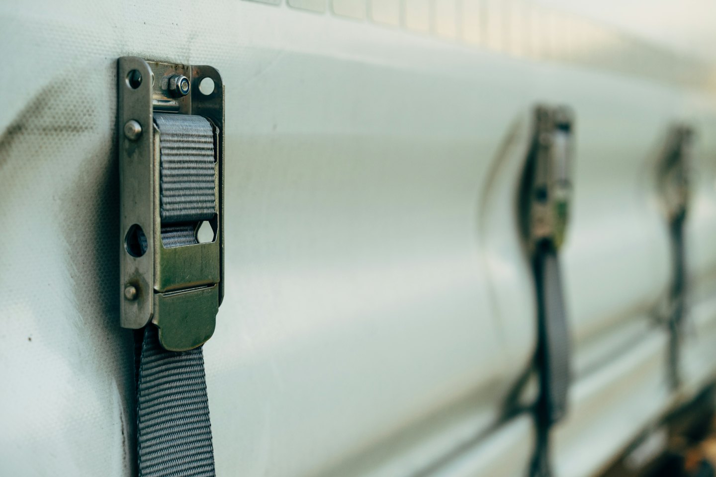 A metal buckle secures a grey strap to canvas material.